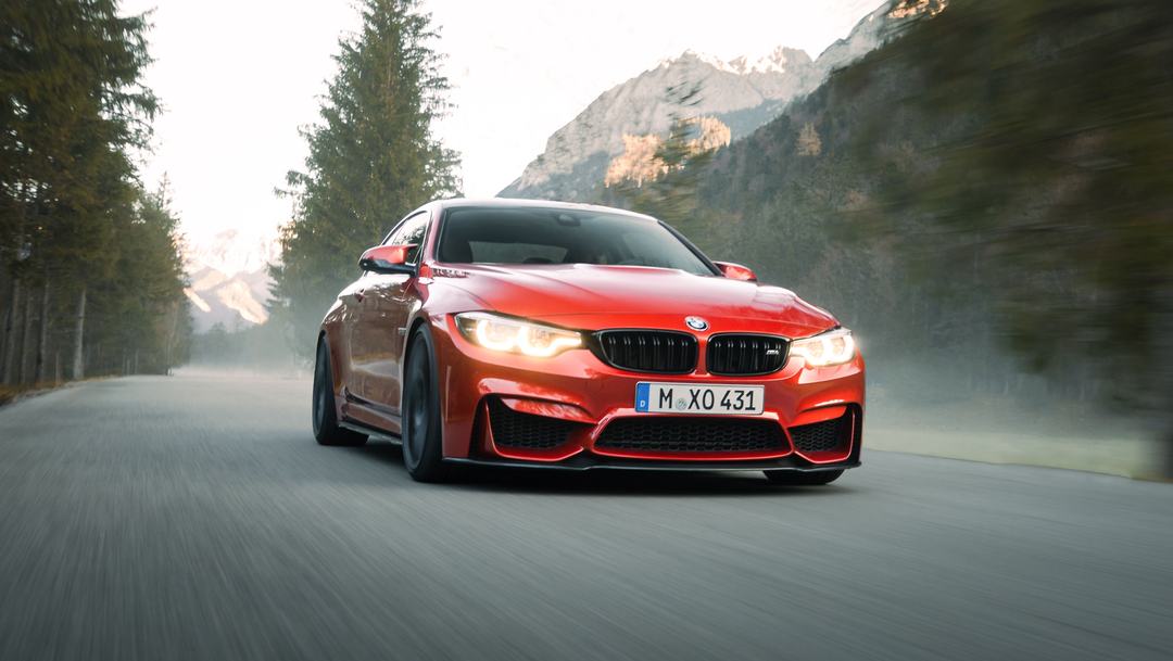 Red BMW M4 driving on a mountain road